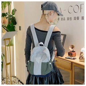 Side view of a tricolor nylon backpack in grey, green, and blue on a female model
