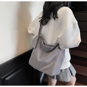 Rear view of a casual grey nylon tote bag with pleated fabric on a female model
