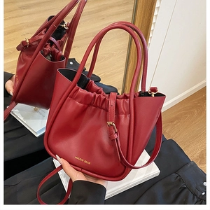 Close-up of pleated burgundy bucket bag with golden hardware and adjustable strap