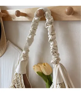 Detail view of woven shoulder bag with unique pleated strap and stylish fringe decoration