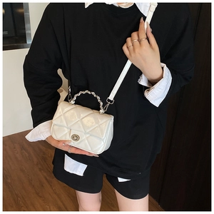 Detail of white quilted crossbody bag with silver chain handle and metallic twist lock