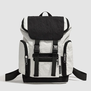 Detail of color-block backpack showing crinkled nylon fabric and buckle closure system