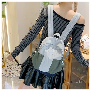 Close-up of lightweight nylon mini backpack with color-block design and side drawstring pockets
