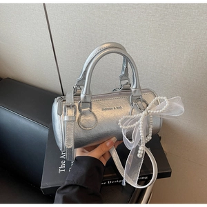 Détail du sac seau cylindrique argenté avec nœud en perles et bandoulière longue