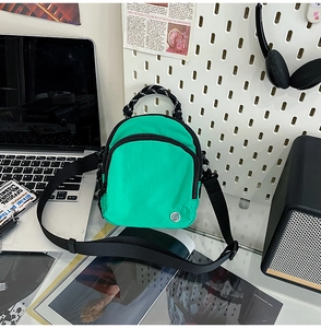 Détail du mini sac bandoulière en nylon vert imperméable avec double fermeture éclair noire