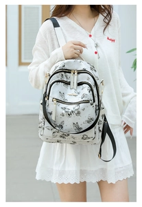 Détail du sac à dos blanc avec imprimés papillons et fermetures éclair dorées élégantes