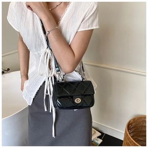 Detail of a black quilted crossbody bag with silver twist lock on a fashion model