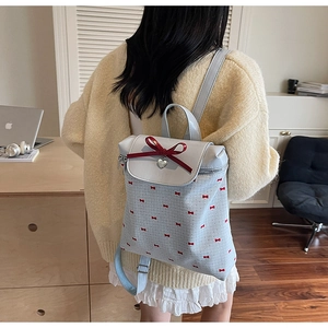Close-up of a light blue bucket bag with a red bow and heart pendant on a model