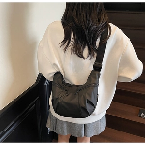 Rear view of model wearing a black nylon crescent crossbody bag with double zip pockets