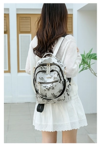 Détail du sac à dos en cuir PU blanc avec imprimé papillon vintage et finitions dorées