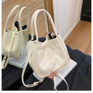 Detailed close-up of cream-white leather bucket bag with gold logo and soft pleated texture