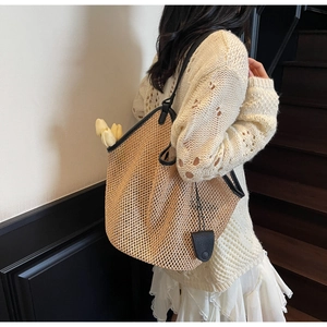 Détail d'un sac cabas en paille tissée avec sangles en cuir noir et tulipes fraîches