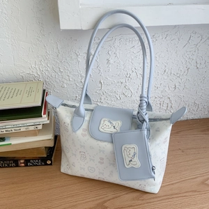 Detail view of large white cat pattern tote bag with matching blue zip pouch on desk