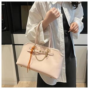 Detail of light pink tote bag featuring gold chain and woven strap with protective feet