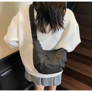 Model view of black nylon crescent bag with adjustable strap and side zipper details