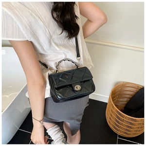 Quilted black leather handbag with silver rotary lock shown worn as a crossbody bag