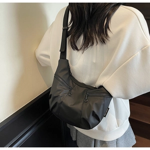 Detail of black nylon crescent bag with multi-zipper pockets and shoulder strap style