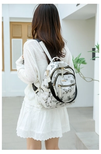 Détail du sac à dos pour femme avec imprimés papillons noirs et zips dorés