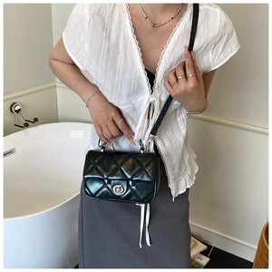 Detail view of a quilted mini crossbody bag with metallic latch and silver chain strap
