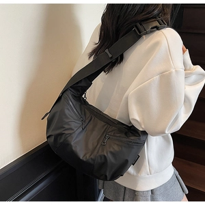 Detail of black nylon crescent bag featuring functional zippers and adjustable wide strap