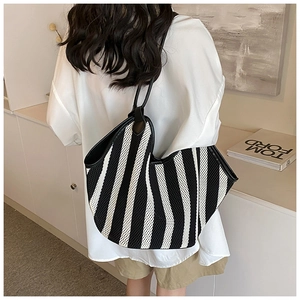 Macro view of a large black and white striped woven tote bag with premium leather handles