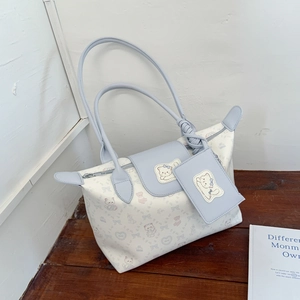 Detail of a white tote bag with light blue accents featuring cute cartoon animal patterns