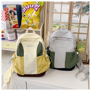 Detail of color-block nylon backpack featuring drawstring side pockets and adjustable straps