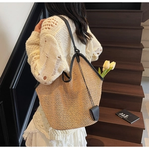Détail du grand sac cabas en paille tissée avec bordure en cuir noir et pompons été