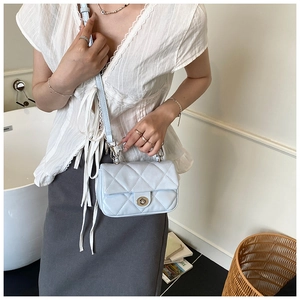 Detail of light blue quilted crossbody bag with silver twist lock and chain strap