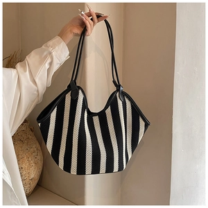 Detail of black and white striped mesh tote bag with black leather handles and trim