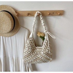 Detail of hollow woven straw bag with cream pleated strap and tulip decoration
