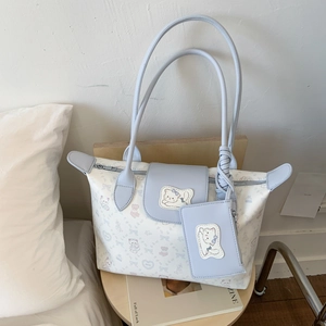 Detail of the cat print tote bag featuring a matching small zip pouch and blue straps