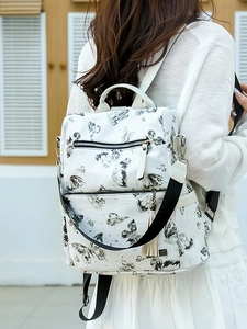 White butterfly print backpack for women with tassel detail and sleek metal brand plaque