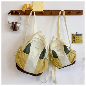 Detailed comparison of large and small color-block backpacks in a warm home setting
