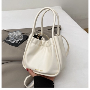 Detailed close-up of cream pleated bucket bag with gold hardware and soft PU leather texture