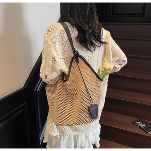 Détail de la texture d'un sac cabas en paille tressée avec anses en cuir noir premium