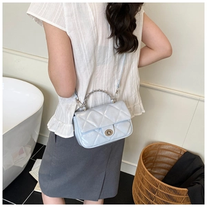 Detail of light blue quilted crossbody bag with silver chain handle and metal twist lock