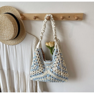 Detailed knit texture of blue and white crochet tote bag with ruffled shoulder strap