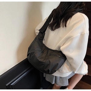 Detail of black nylon crossbody crescent bag with functional multi-zipper pockets
