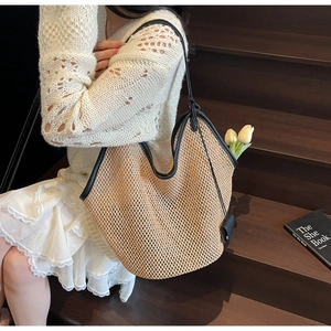 Détail du sac cabas en paille tissée avec bordures et anses en cuir noir contrasté