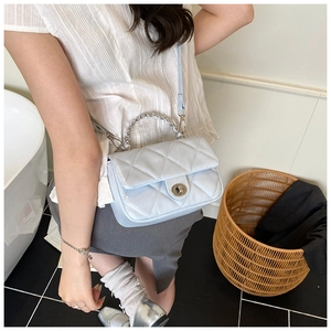 Detailed close-up of light blue quilted crossbody bag with silver chain and twist lock