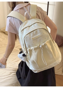 Side view of cream backpack with star prints and panda plush charm on a model