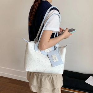 Detailed view of a white tote bag with cute cat prints and a blue coin purse