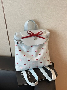 White backpack with red bow print, heart pendant and large bow detail on the front flap