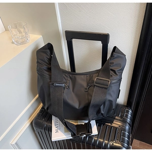 Detail of black crescent crossbody bag with durable nylon strap on a suitcase