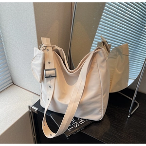 Detail of beige tote bag with wide strap, metal buckle and matching mini coin purse pouch