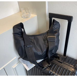 Close-up of black crescent nylon shoulder bag on a suitcase for travel and commute