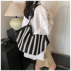 Black and white striped mesh tote bag with leather straps shown from a side view
