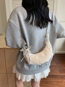 Minimalist beige crescent bag with silver star charm shown on a female model