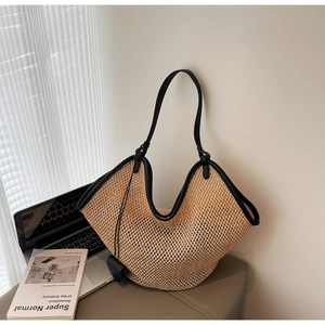 Close-up of woven straw tote bag with black leather trim on a minimalist chair